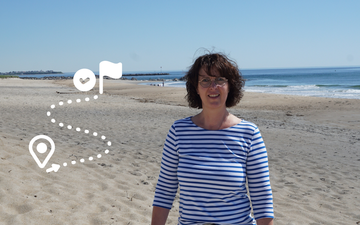 Manuela Weinand am Strand mit einem Symbol für den Weg vom Start bis zum Ziel.