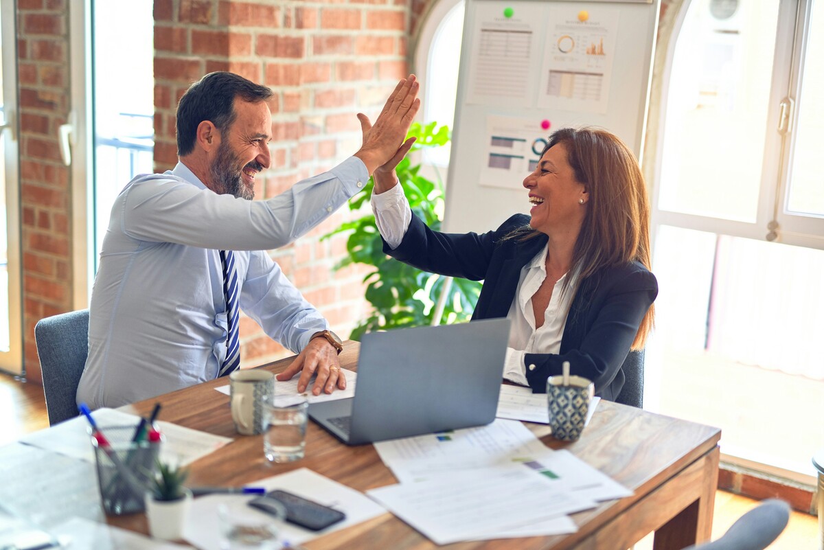 Mann und Frau im Business. Sie geben sich ein High Five.